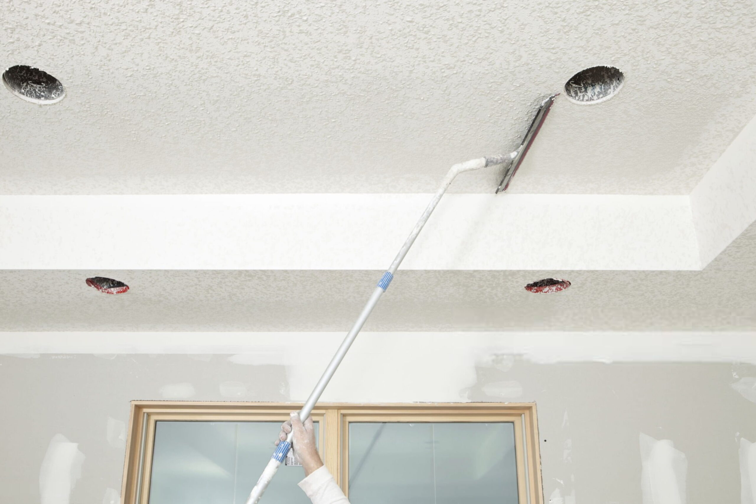 Worker Troweling Drywall Mud on a Ceiling for Knockdown Text